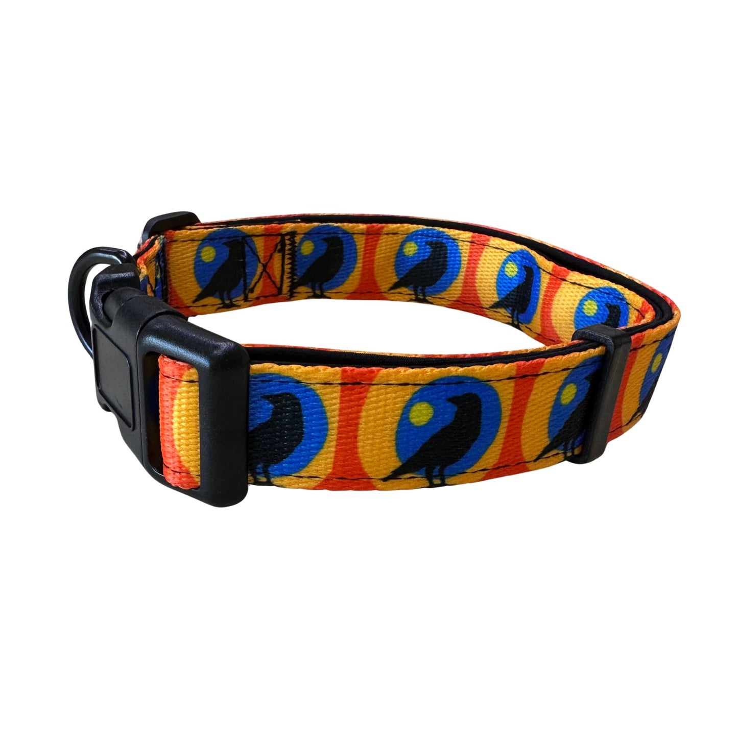 The Rustic County Sunset Crow Adjustable Pet Collar is a yellow and orange collar with blue and black bird designs, featuring a black plastic buckle and metal D-ring for comfort and style.