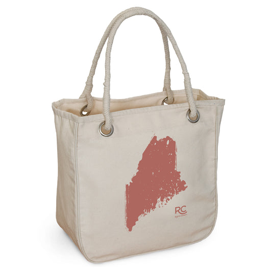An eco-friendly Maine Rope Tote by Rustic County with a red splatter design resembling a map outline on one side, featuring a printed logo 'rc' in the lower right corner and two sturdy rope handles.