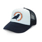 A Rustic County Trucker Hat - Blue with a white front panel featuring a logo of the Rustic County Crow silhouette inside an orange circle, and dark navy mesh back panels.