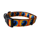 The Rustic County Sunset Crow Adjustable Pet Collar is a yellow and orange collar with blue and black bird designs, featuring a black plastic buckle and metal D-ring for comfort and style.