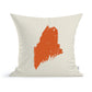 A State of Maine Pillow from Rustic County, featuring a minimalist orange paint-splatter design resembling the shape of Maine on a cream background.