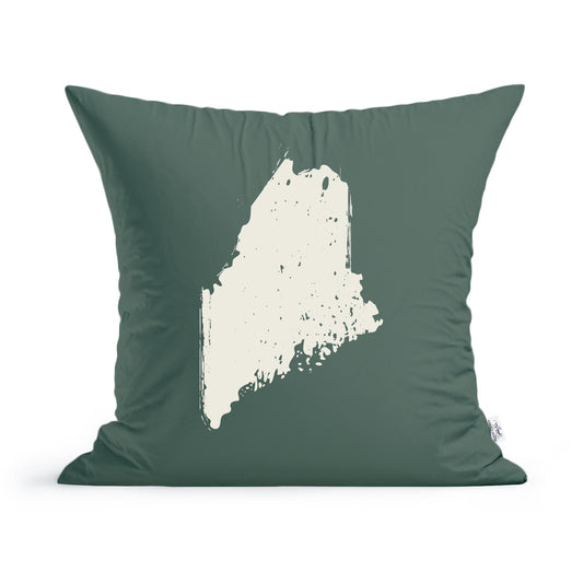 A green cotton State of Maine pillow cover featuring a white silhouette of the state of Maine in a distressed style, set against a solid background. This machine-washable Rustic County throw pillow is square-shaped.
