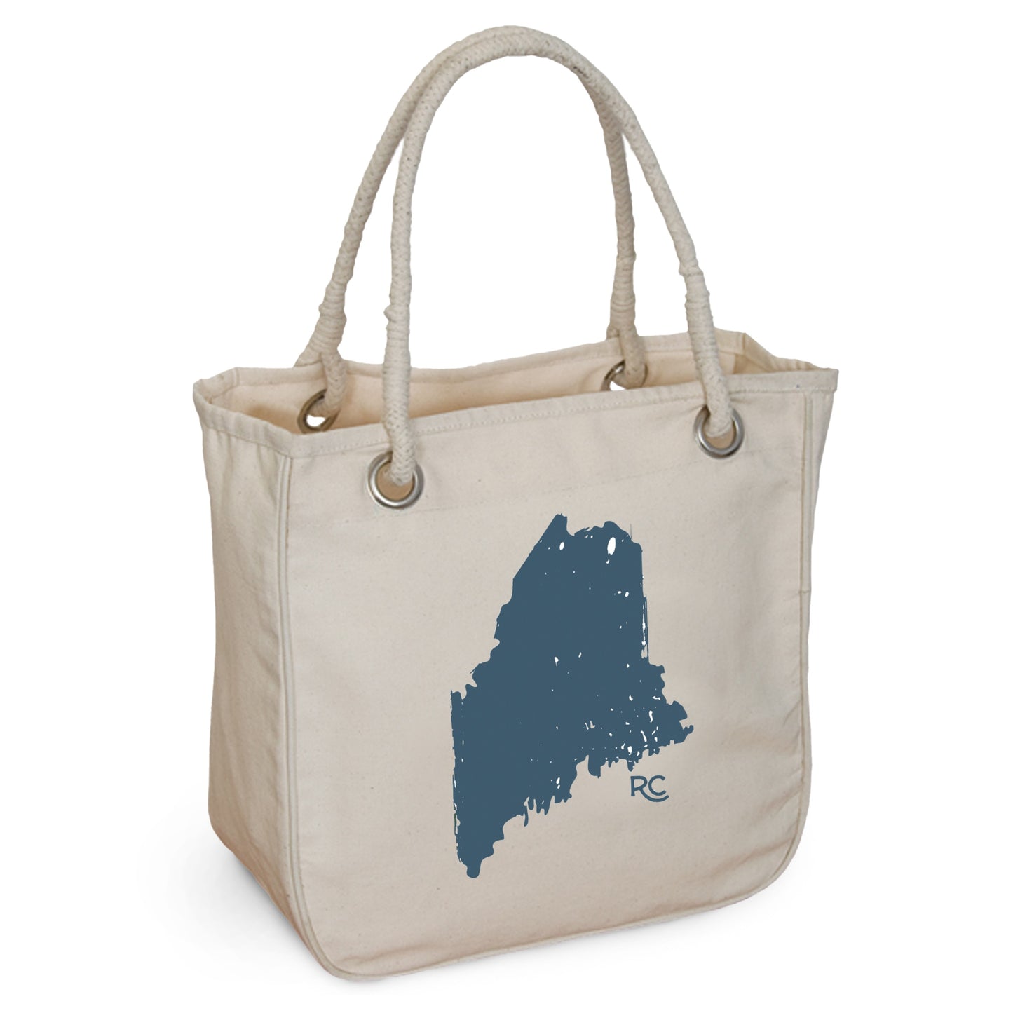 The Maine Rope Tote from Rustic County is made of organic cotton, featuring beige canvas, rope handles, and a blue state silhouette with "RC" initials. It embodies eco-friendly style for daily use.