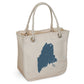 The Rustic County Maine Rope Tote is an eco-friendly, cream-colored organic cotton bag with sturdy rope handles, a bold blue Maine silhouette, and "RC" initials printed near the bottom right for local charm.