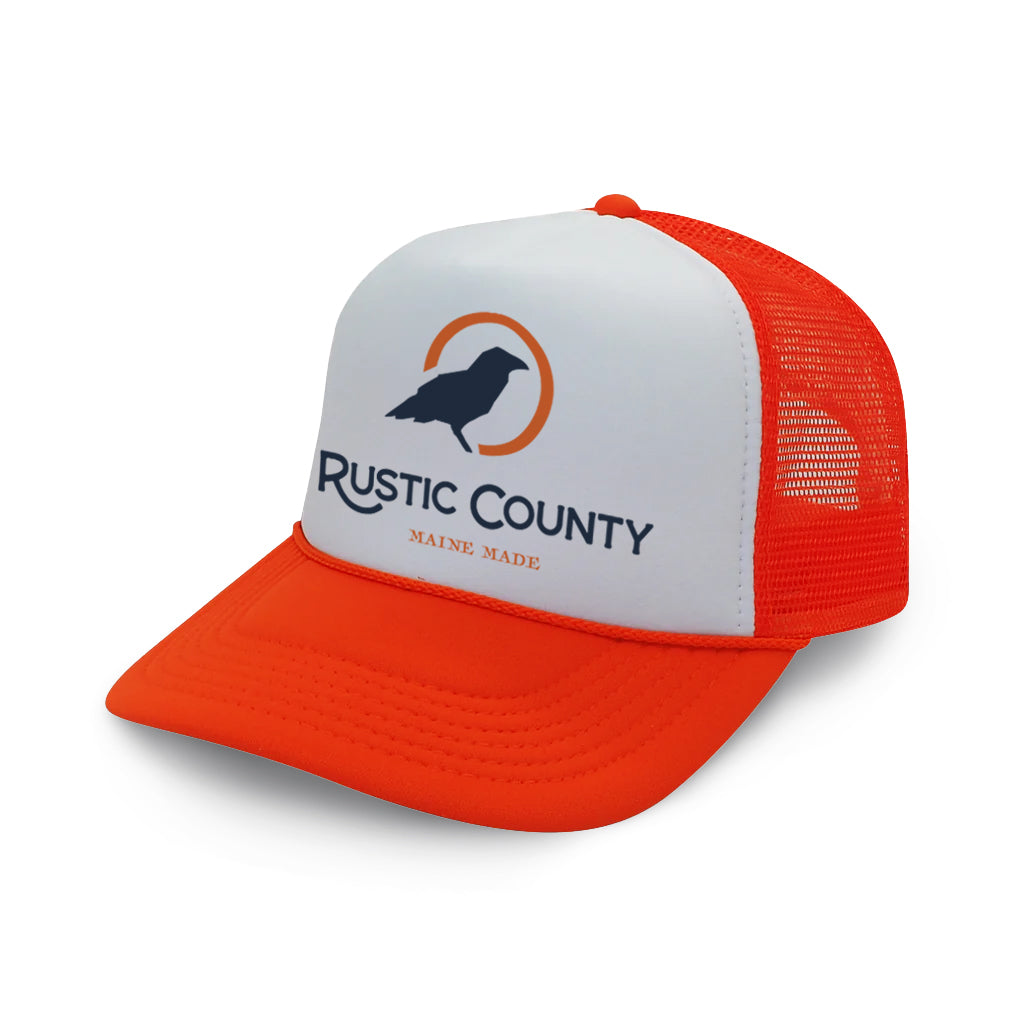 Blaze orange and white Rustic County Trucker Hat - Orange with a mesh back, featuring a logo of a bird in silhouette and the text "Rustic County - Maine Made" on the front panel.